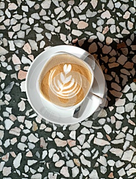 Cup of flat white coffee with latte art on terrazzo tile table top