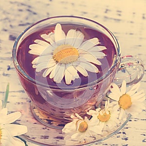 Cup of fragrant chamomile tea tea, in white chamomile flowers