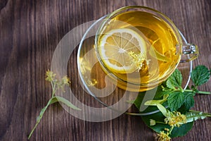 Cup with fragrant lime tea, standing on a wooden table, in the rays of sunlight