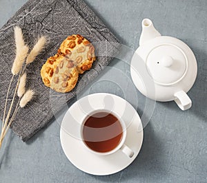 A cup of fragrant tea with homemade cookies and a white teapot on a blue background. Delicious breakfast concept