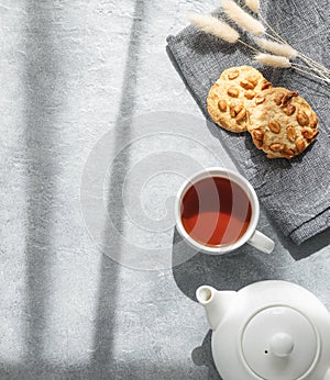 A cup of fragrant tea with homemade cookies and a white teapot on a blue background in the morning sunlight. Delicious breakfast