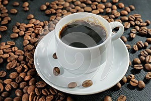 A cup of fresh, black coffee and roasted coffee beans, close-up