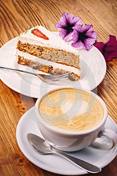 Cup of fresh cappuccino coffee with delicious piece of carrot cake on the wooden table