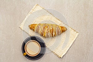 A cup of fresh coffee with croiA cup ossant. The concept on a stone background, vintage linen napkin, top view, flat lay, close up photo