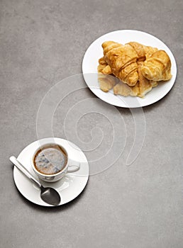 Cup of fresh coffee with croissants on dark background