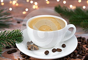 Cup of fresh coffee on the wooden table. Christmas lights garland on background. Festive mood. Close-up. Selective focus