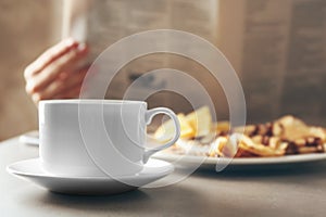 Cup of fresh hot coffee and breakfast on table