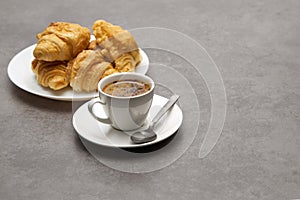 Cup of fresh coffee with croissants on dark background