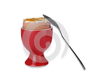 Cup with fresh soft boiled egg and spoon on white background