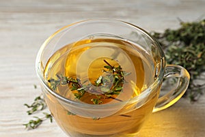 Cup of fresh thyme tea on table, closeup