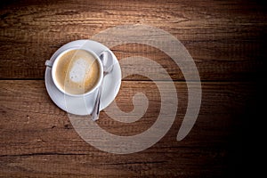 Cup of freshly brewed aromatic cappuccino standing on a wooden t