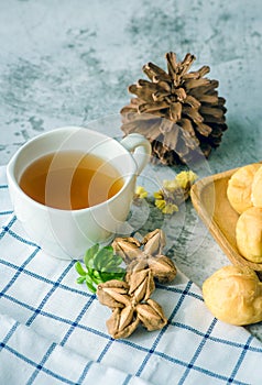 A Cup of freshly brewed tea Inchi peanut,escaping steam,warm soft light, with Eclair sweet on the table