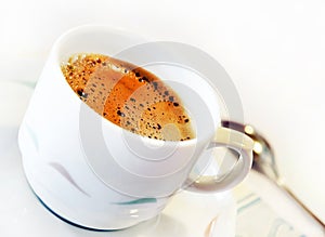 Cup of freshly coffee on saucer with spoon