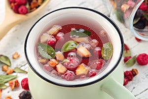 Cup of fruit tea with apples, orange, red and black currant berries