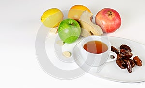 Cup of fruit tea, limon, green apple, garnet, ginger, dates and multivitamins  isolated on the white background. Antiviruses