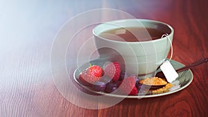 Cup of fruit tea with strawberries, raspberries and blueberries on wooden table, with copy space.