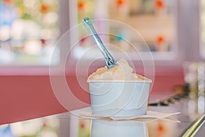 Cup of fruty ice cream pouring in shop