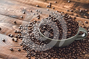 Cup full of Black coffee grains lie on a brown wooden table, background image. Coffee beans in a green cup