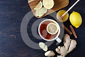 Cup of ginger tea with lemon and honey on dark background. Top view. Antiviral Healthy useful drink.