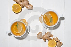 Cup of Ginger Tea with Lemon and Honey on a White Wooden Background.