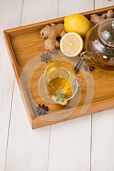 Cup of ginger tea with lemon and honey on white wooden background.