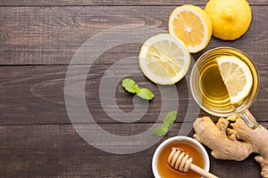 Cup of ginger tea with lemon and honey on wooden background