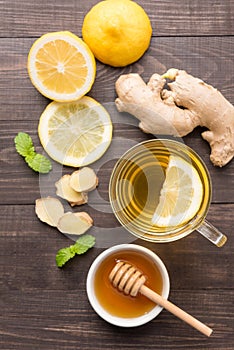 Cup of ginger tea with lemon and honey on wooden background