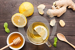 Cup of ginger tea with lemon and honey on wooden background