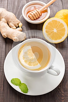 Cup of ginger tea with lemon and honey on wooden background