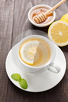 Cup of ginger tea with lemon and honey on wooden background