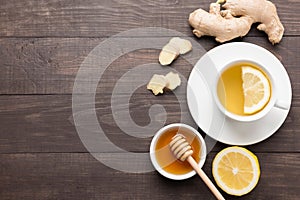 Cup of ginger tea with lemon and honey on wooden background. Cop