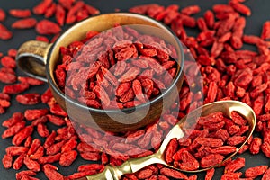 Cup with Goji berries and vintage spoon on gray slate. View from above, selective focus