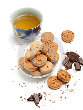 Cup of green chinese tea, tasty biscuit cookies and dark chocolate pieces and chips lie isolated on white background