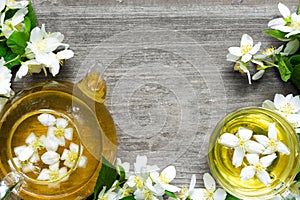 Cup of green herbal tea with jasmine flowers and teapot