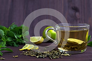 Cup of green tea with fresh lime on dark wooden table