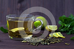 Cup of green tea with fresh lime on dark wooden table