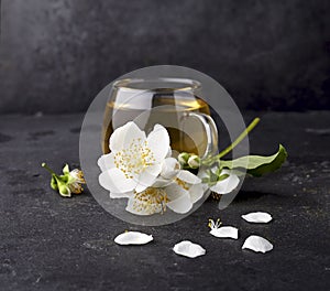 Cup of green tea and Jasmine flowers on a black background. Herbal medicine