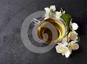 Cup of green tea and Jasmine flowers on a black background. Herbal medicine