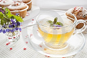 Cup of green tea with lemon balm and tasty muffins with sugar hearts