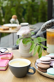 Cup of green tea with pastel colors pastry macarons on a wooden table top view