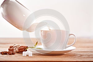 Cup with green tea, sugar and teapot on light wooden table background