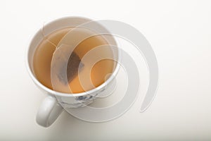 A cup of green tea with tea bag on a white background