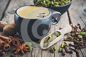 Cup of healthy ayurvedic masala tea or coffee with aromatic spices. Cinnamon sticks, cardamom, allspices and anise on table