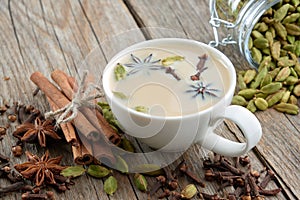 Cup of healthy ayurvedic masala tea or coffee with milk and aromatic spices. Cinnamon sticks, cardamom, cloves and anise stars