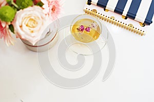A cup of healthy herbal tea with dried roses. Beautiful fresh flowers, notebooks on light marble table, top view. Pink roses and g