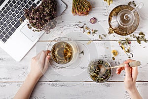 Cup of healthy tea, honey, healing herbs, herbal tea assortment and berries on table. Top view. Herbal medicine.