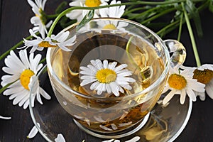 Cup of herbal chamomile tea with fresh daisy flowers on wooden background. doctor treatment and prevention of immune concept