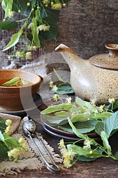 Cup of herbal leme leaf tea with linden flowers on old wooden background