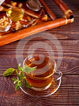 Cup of herbal mint tea with dry herbs on the tray.