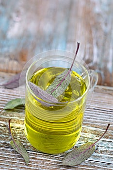 Cup of herbal sage tea with fresh leaves on rustic background , health concept, close up